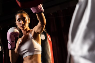 Asyalı kadın Muay Taylandlı boksör boks antrenmanını yumrukluyor idman antrenörüne boks eldiveni takıyor, Muay Tay boks tekniği ve becerisi sergiliyor. Impetus