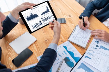 Ofisteki analist ekibi, iş performansını artırmak için tablet ekranında grafik ve grafik olan BI panelini kullanarak çalışma alanındaki pazarlama stratejisi için finansal veri analizi yapmakla meşgul. Varlık