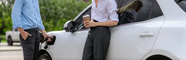 Progressive Businessman Businesswoman Coffee Standing Electric Car Connected Charging Station — Φωτογραφία Αρχείου