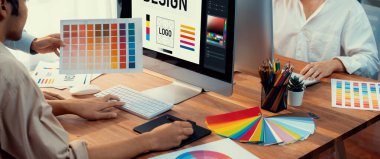 Grafik tasarımcısı, modern dijital stüdyo işyerinde profesyonel grafik ekibiyle benzersiz bir tasarım yaparken bilgisayar dizüstü bilgisayar ve grafik çizim kalemi üzerinde çalışır. Panorama çekimi. İnceleyin
