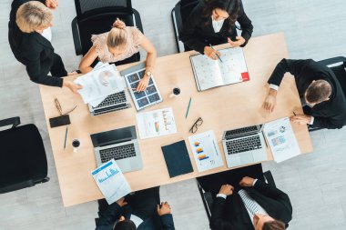 İş adamları grup toplantısı ofiste yukarıdan çekildi. İş kadınları, iş adamları ve ofis çalışanları toplantı masasında proje planlama belgeleriyle takım konferansında çalışıyorlar. Jivy