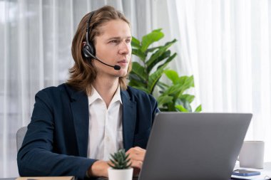 Erkek müşteri hizmetleri operatörü ya da telesales temsilcisi ofiste oturuyor, kulaklık takıyor ve müşteriyle satış desteği ya da kapanış konuşması yapıyor. Çağrı merkezi portresi. Varlık