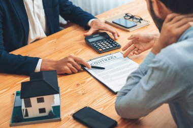 Emlakçı vergi ve faizi hesaplıyor, müşteriyle emlak satın alma ve ev kredisi başvurusunda bulunma şartları. Finansal danışman, yatırım bütçesini hesap makinesiyle yönetiyor. Varlık