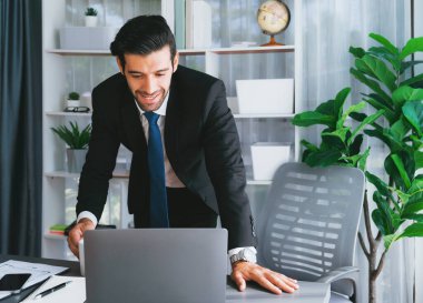 Modern ofis masasındaki modern profesyonel iş adamı çalışmak ve notlar yazmak için dizüstü bilgisayar kullanıyor. Ofisinde bilgisayar defteri üzerinde çalışan çalışkan bir ofis çalışanı. coşkulu