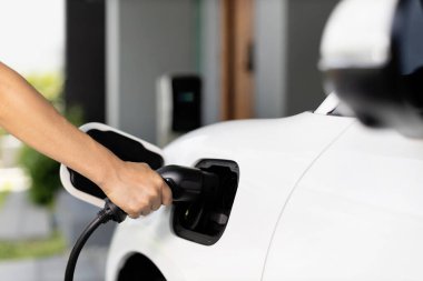 Progressive concept of hand insert an emission-free power connector to the battery of electric vehicle at home. Electric vehicle charging via cable from charging station to EV car battery