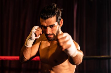 Üstsüz boksör pozu veren, beyaz boksör yumruğunu yumruklayıp kameranın önüne geçiyor, agresif duruşunu takınıyor ve boks ringinde dövüşmeye hazır. Impetus