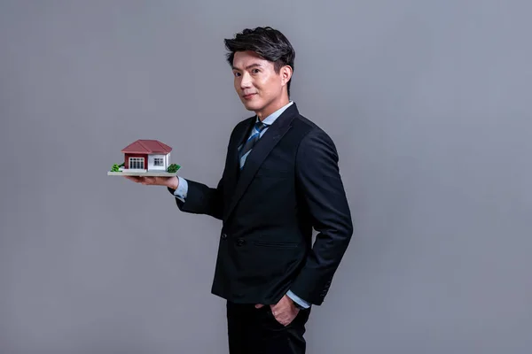 自信的亚洲商人拿着房子模型 笑着做广告贷款 具有样板房模型的房地产经纪人手头有独立的住房商业广告背景 — 图库照片