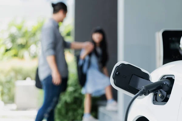 将电动车充电集中在家里的充电站 父亲和女儿在后台走来走去 促进健康环境生活方式概念的渐进式绿色清洁能源工具 — 图库照片