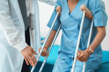 Doktor hastanede koltuk değnekli hastayla ilgileniyor. Fizyoterapist ve bacak yaralanması konsepti. Jivy