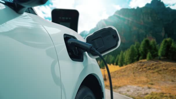 電気発生器ドライブによるエネルギー持続可能な車の電源 プログレッシブ旅行の概念のための山の背景と充電ステーションでバッテリーを充電します クリーン環境のシンボルとして自然界のEv車 — ストック動画