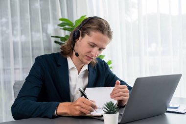 Erkek müşteri hizmetleri operatörü ya da telesales temsilcisi ofiste oturuyor, kulaklık takıyor ve müşteriyle satış desteği ya da kapanış konuşması yapıyor. Çağrı merkezi portresi. Varlık