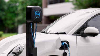 Elektrikli araba EV şarj kablosu ile şarj olmak için şarj istasyonuna bağlı. Geleceğin yenilikçi EV arabası ve enerji sürdürülebilirliği. Akıllı ve fütüristik ev enerjisi altyapısı. İnceleyin