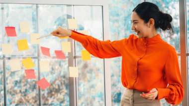 İş adamları ofisteki proje planlama kurulunda çalışıyor ve proje gelişimini analiz etmek için iş arkadaşlarıyla sohbet ediyorlar. Düzenli olması için cama yapıştırılmış yapışkan notlar kullanıyorlar. Jivy