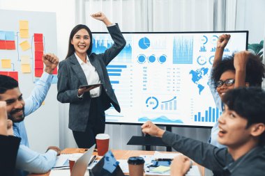 İş adamları TV ekranında başarılı bir sunum veya veri analizi toplantısından sonra kutlama yapıyorlar. Mutlu takım ofis odasında toplanıyor, kutlama jestleriyle işbirliği için tezahürat yapıyorlar. Uyum