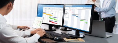 Projeyi koordine eden ve güncelleyen proje ekibi Gantt çizelge yazılımını kullanarak bilgisayarda program planladılar. Şirket işi için zaman ve süre belirleyen iş adamları. Önde.