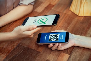 QR kodu parasız ödeme taraması için ekranda gösterilir. Kapalı eller, mobil uygulamadan elektronik işlem yoluyla para aktarmak için akıllı telefonu tutuyor. Hızlı ödeme için barkod teknolojisi. Coşkulu.