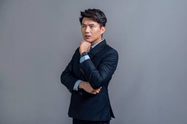 Kendine güvenen Asyalı patronluk taslayan iş adamı profesyonel siyah takım elbiseli, izole bir arka planda poz veriyor. İşletme terfisi ve reklam için ofis çalışanlarının başarısı. Sevinçli.