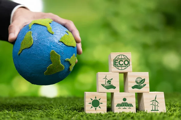 商人手拿着带有生态符号和纸地球仪的木制立方体 背景肥沃 环境意识和可持续能源 清洁和可再生能源促进更绿色的生态 改变了 — 图库照片