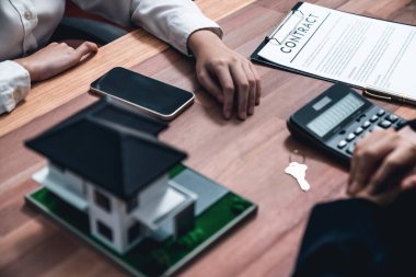 Temsilciyle ev kredisi sözleşmesini gözden geçiriyorum. Mali belgeleri ve vergi oranlarını, mülkiyet sahibi olmak için hesap makinesiyle analiz ediyorum. Yeni ev alımı ve finansman için anahtar imza. Coşkulu.