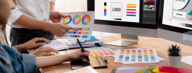 Grafik tasarımcısı, modern dijital stüdyo işyerinde profesyonel grafik ekibiyle benzersiz bir tasarım yaparken bilgisayar dizüstü bilgisayar ve grafik çizim kalemi üzerinde çalışır. Panorama çekimi. İnceleyin