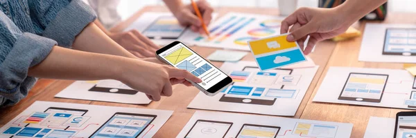 stock image Panorama shot of front-end developer team brainstorming UI and UX designs for mobile app on paper wireframe interface. User interface development team planning for user-friendly UI design. Scrutinize