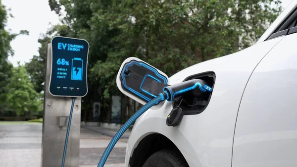 充電ステーションに接続された電気自動車は エコグリーンパークや緑の葉でEv充電ケーブルでバッテリーを充電します 将来の革新的なEv車とエネルギー持続可能性 — ストック写真