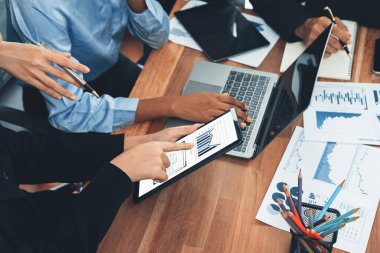 Çok ırklı analist ekibi toplantı masasındaki finansal verileri analiz etmek için BI Fintech yazılımı kullanıyor. Finansal konsol veri ekranında pazarlama göstergesi için analiz edilmiş grafikle birlikte. Uyum