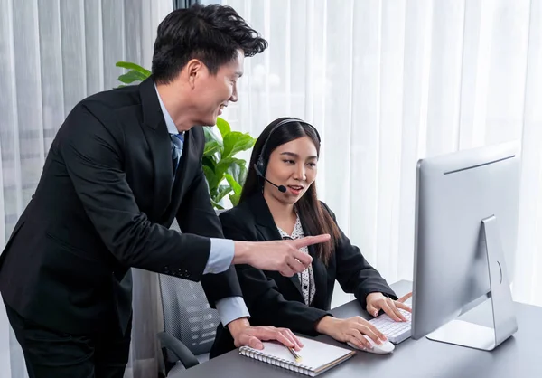 stock image Manager helps female call center operator with customer support. Asian woman call center in headset and microphone gets guidance in modern office. Efficient teamwork for telesales service. Jubilant