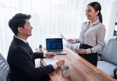 Görüşmeci ve aday arasındaki iş görüşmesi. İK müdürü aday niteliklerini ve özgeçmişli iş başvurusunu soruyor. Başvuru sahibinin işi. Sevinçli.