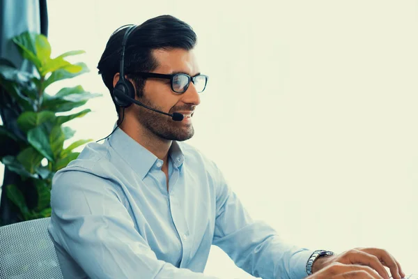 stock image Male call center operator or telesales representative siting at his office desk wearing headset and engaged in conversation with client providing customer service support or making a sale. fervent