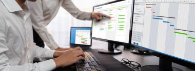 Projeyi koordine eden ve güncelleyen proje ekibi Gantt çizelge yazılımını kullanarak bilgisayarda program planladılar. Şirket işi için zaman ve süre belirleyen iş adamları. Önde.