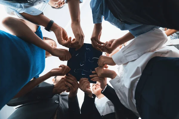 stock image Below view of diverse corporate officer workers collaborate in office connecting puzzle pieces as partnership and teamwork concept. Unity and synergy in business idea by merging jigsaw puzzle. Concord