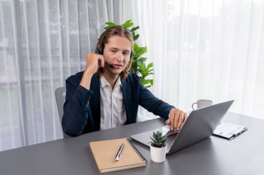 Erkek müşteri hizmetleri operatörü ya da telesales temsilcisi ofiste oturuyor, kulaklık takıyor ve müşteriyle satış desteği ya da kapanış konuşması yapıyor. Çağrı merkezi portresi. Varlık