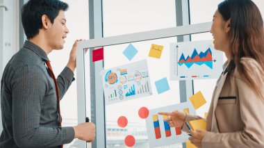 İş adamları ofisteki proje planlama kurulunda çalışıyor ve proje gelişimini analiz etmek için iş arkadaşlarıyla sohbet ediyorlar. Düzenli olması için cama yapıştırılmış yapışkan notlar kullanıyorlar. Jivy