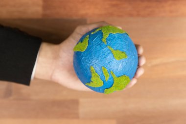 Üst düzey iş adamları kağıt toprağı masanın üstünde tutarlar. Temiz enerji ve sıfır CO2 emisyonu kullanan sürdürülebilir dünya için çevre bilinci. Yeşil politikası olan çevre dostu bir şirket. Değiştir