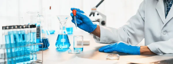 科学者は医学実験室で化学実験を行い 正確な液体をピペットからワクチン薬や抗生物質の開発のための試験管に慎重に落下させる — ストック写真
