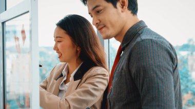 İş adamları ofisteki proje planlama kurulunda çalışıyor ve proje gelişimini analiz etmek için iş arkadaşlarıyla sohbet ediyorlar. Düzenli olması için cama yapıştırılmış yapışkan notlar kullanıyorlar. Jivy