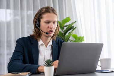 Erkek müşteri hizmetleri operatörü ya da telesales temsilcisi ofiste oturuyor, kulaklık takıyor ve müşteriyle satış desteği ya da kapanış konuşması yapıyor. Çağrı merkezi portresi. Varlık