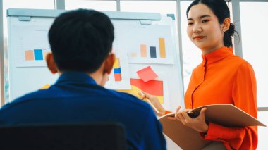 Genç bir kadın günlük ofis odasındaki beyaz tahtadaki iş verilerini açıklıyor. Kendine güvenen Asyalı iş kadını, strateji belirleme amaçlı bir iş projesinin bilgi ilerlemesini bildiriyor. Jivy