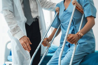 Doktor hastanede koltuk değnekli hastayla ilgileniyor. Fizyoterapist ve bacak yaralanması konsepti. Jivy