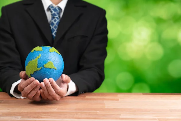 stock image Businessman holds paper earth as symbol of eco environmental awareness for sustainable world using clean energy and zero CO2 emission. Eco-friendly corporate with go green policy to save earth. Alter