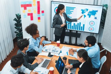 Modern toplantı odasındaki TV ekranında veri analizi paneliyle üst görünüm iş sunumu. İş adamlarının iş pazarlama stratejisini planlamak için beyin fırtınası yapması ya da birlikte çalışması. Uyum
