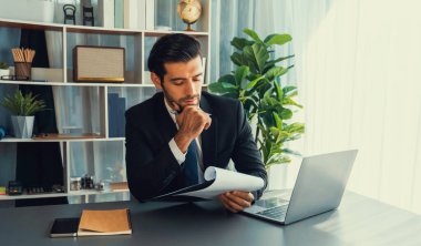 Modern ofis masasındaki modern profesyonel iş adamı çalışmak ve notlar yazmak için dizüstü bilgisayar kullanıyor. Ofisinde bilgisayar defteri üzerinde çalışan çalışkan bir ofis çalışanı. coşkulu