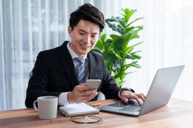 Ofis masasında dizüstü bilgisayarda çalışan bir iş adamı. Akıllı yönetici finansal iş verilerini araştırıyor ya da masada bilgisayarla stratejik iş pazarlaması planlıyor. Sevinçli.