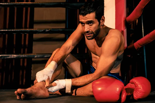 stock image Caucasian boxer with pain and injury after intense boxing training or fighting match, sitting at the edge of ring. Physical injury in sport concept. Impetus