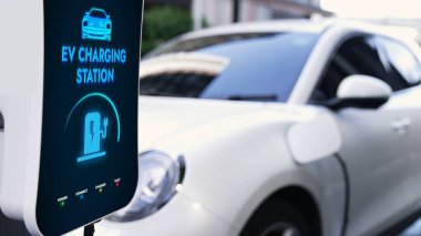 Otoparkta şarj edilen EV şarjlı elektrikli araba. Alternatif temiz ve sürdürülebilir enerji kullanan geleceğin yenilikçi yenilenebilir EV arabası. İnceleyin