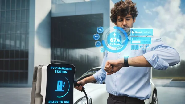 Üzletember Ellenőrizze Autó Akkumulátor Állapotát Smart Watch Hologramon Miközben Feltöltődik — Stock Fotó