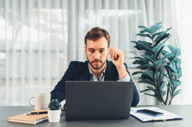 Siyah takım elbiseli bir iş adamı çalışma masasında dizüstü bilgisayarla çalışıyor. Akıllı yönetici finansal verileri araştırıyor ve modern işyerindeki kurumsal dizüstü bilgisayarlarda pazarlama stratejisi planlıyor. Varlık