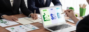 ESG 'nin çevresel sosyal yönetimi, çevre dostu şirket toplantılarında, temiz ve sürdürülebilir gelecekteki ekoloji için çevre korumasını uygulayan iş adamlarıyla dizüstü bilgisayarda sergileniyor. Önde.