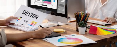 Grafik tasarımcısı, modern dijital stüdyo işyerinde profesyonel grafik ekibiyle benzersiz bir tasarım yaparken bilgisayar dizüstü bilgisayar ve grafik çizim kalemi üzerinde çalışır. Panorama çekimi. İnceleyin